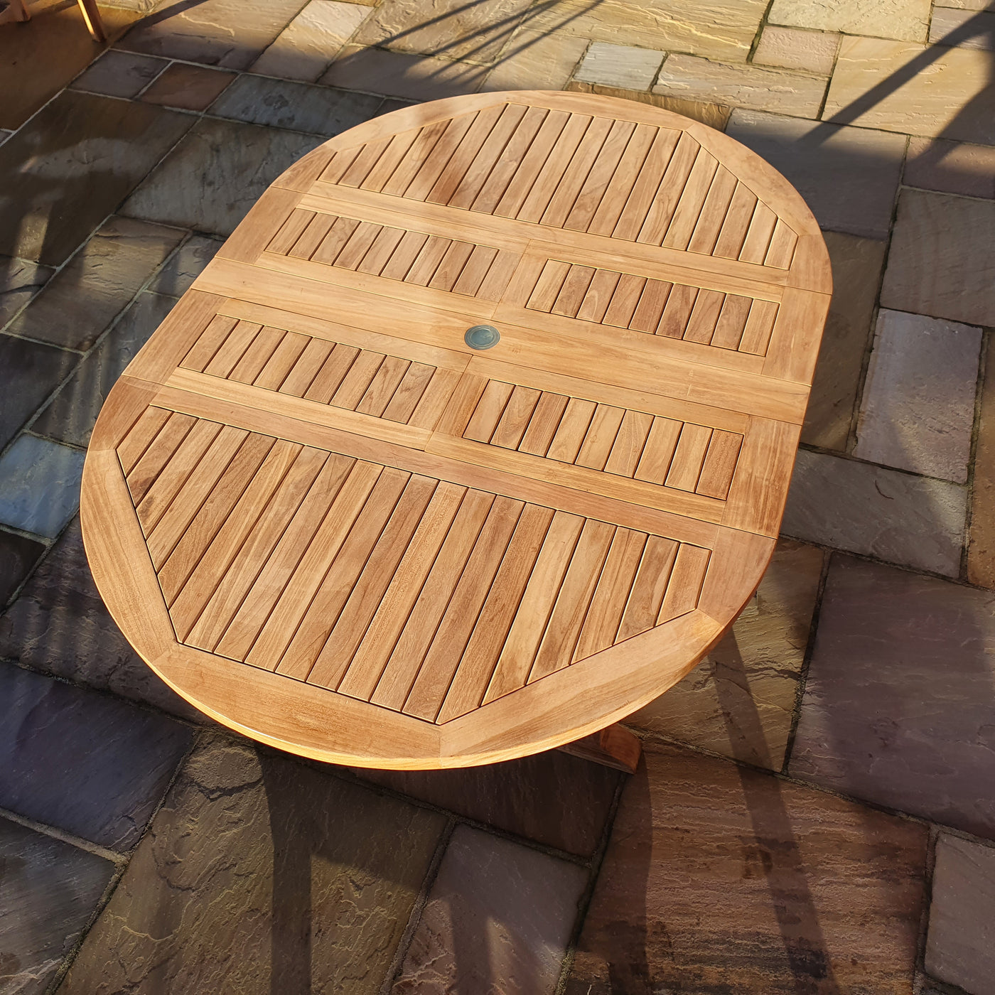 Round To Oval 120-170cm Extending (6 Seat Oxford Stacking Set) Complete set Cushions Free Delivery outdoors on a paved surface, capturing the textures under natural lighting.