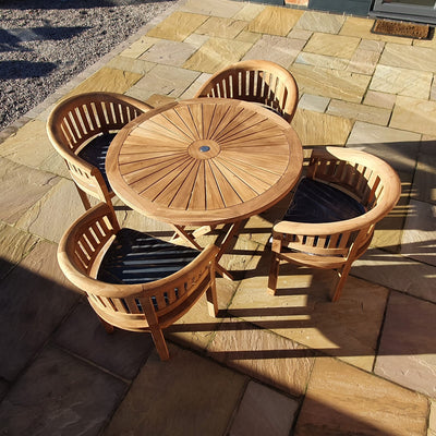 Teak 120cm Sunshine Set with 4 San Francisco Chairs table with four matching chairs on a stone paved terrace, bathed in sunlight.