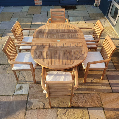 Round To Oval 120-170cm Extending (6 Seat Oxford Stacking Set) Complete set Cushions Free Delivery garden dining table with six chairs set on a stone patio during clear weather.