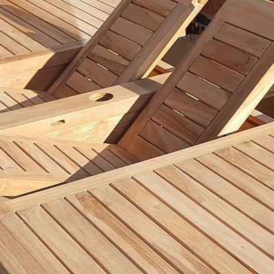 Teak 180-240cm Oval Extending Table with 8 Henley Stacking Chairs featuring a circular cutout, set on a sunny deck.