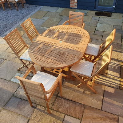 Oval 120-170cm Extending dining set with one round table and six chairs on a paved patio, in sunlight.