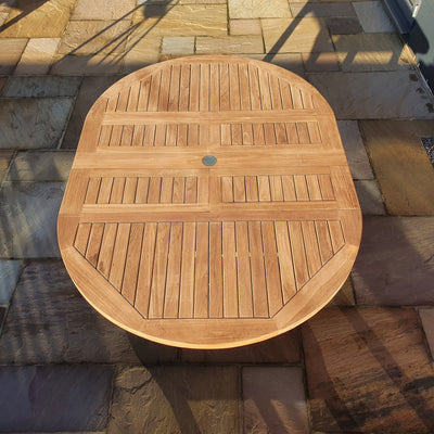 A Round To Oval 120-170cm Extending Table on a tiled patio, illuminated by sunlight with a shadow cast on one side.