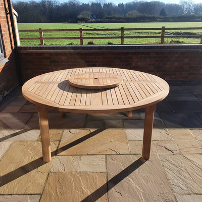 Teak 180cm Round Maximus Set (3 San Francisco Benches) Complete set Cushions Included on a stone patio with a rural landscape and a wooden fence in the background.