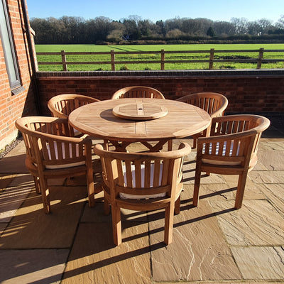 Teak 150cm Maximus Table Set with 6 San Francisco Chairs outdoor dining table with eight chairs on a paved patio, overlooking a sunny rural landscape.