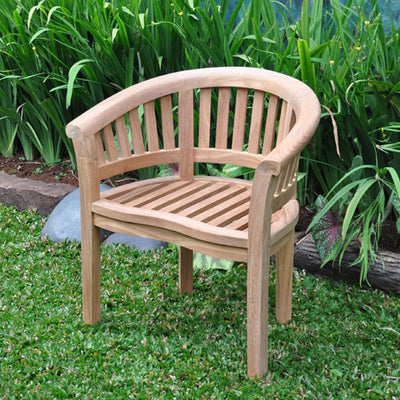 Teak 150cm Maximus Table Set with 6 San Francisco Chairs on a grassy patch, surrounded by lush green plants.