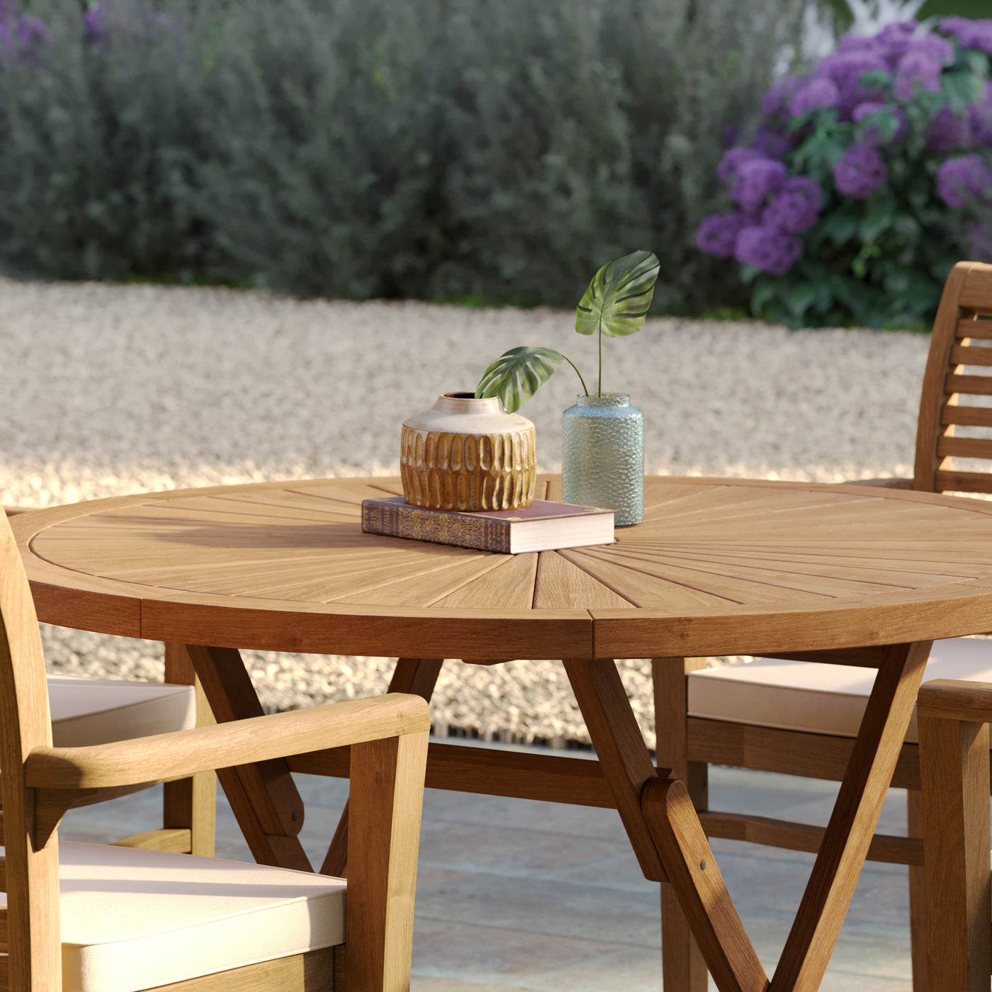 Close-up of 120cm round teak Sunshine table and Oxford stacking chairs, showcasing the teak garden furniture's smooth finish.