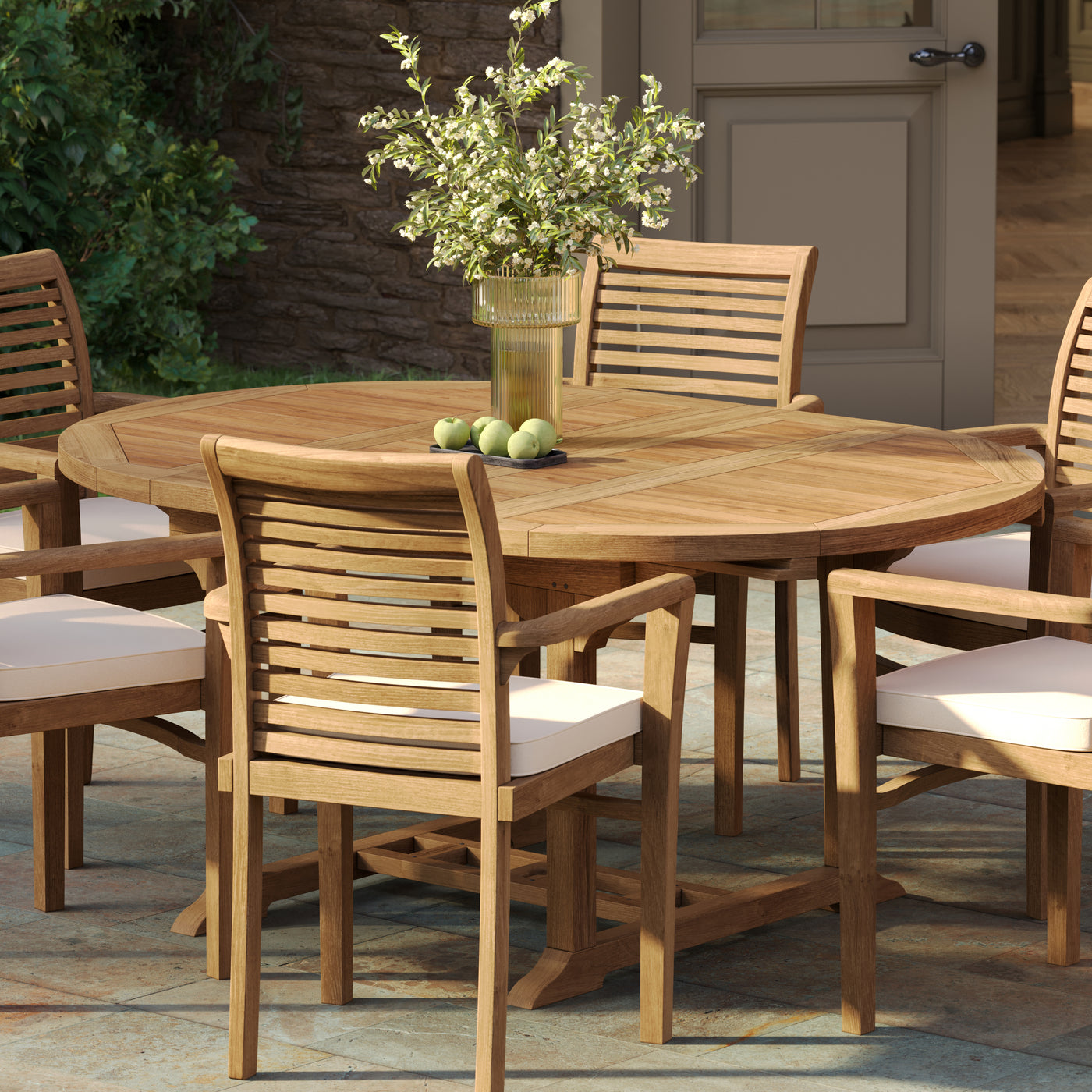 Teak garden furniture set featuring an extending round to oval teak table and six Oxford stacking chairs in a scenic garden setting.